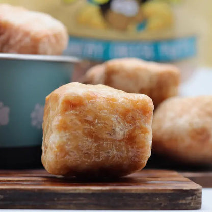 Dog treats on a wooden board with a bowl in the background