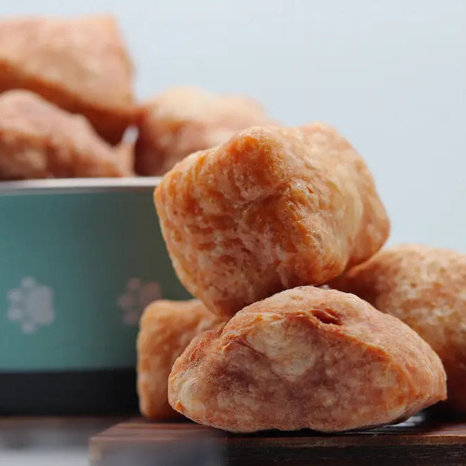 Dried persimmons stacked on a wooden board with a teal bowl in the background.