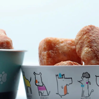 Two bowls filled with dog treats on a light blue background.